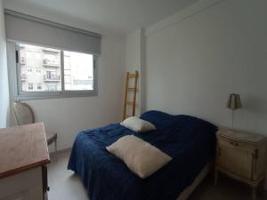 um quarto com uma cama com um cobertor azul e uma janela em Departamentos 2 ambientes en Mar del Plata em Mar del Plata