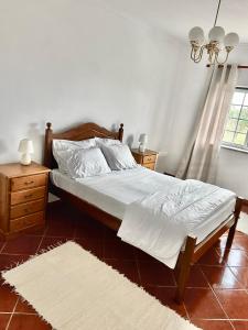 Schlafzimmer mit einem Bett mit weißer Bettwäsche und einem Fenster in der Unterkunft MaJô Alojamento Local in Tábua