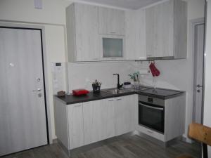 a kitchen with white cabinets and a sink and a stove at Cozy & Stylish Eastside Apt. in Thessaloniki