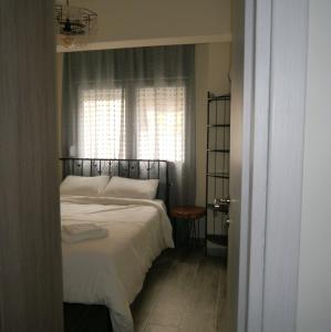 a bedroom with a bed with white sheets and a window at Cozy & Stylish Eastside Apt. in Thessaloniki