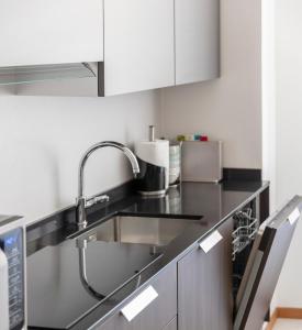 una cocina con fregadero de acero inoxidable y armarios blancos en RivApartmentsDowntowN Travel en Riva del Garda
