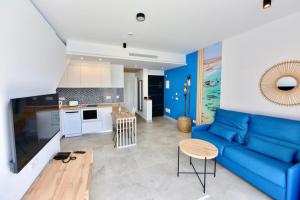 uma sala de estar com um sofá azul e uma cozinha em LACASA Apartments Cotillo em Cotillo