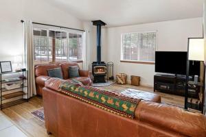 a living room with a leather couch and a wood stove at Indio Cabin in Bend