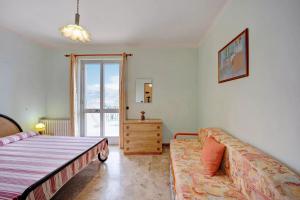 a bedroom with a bed and a couch and a window at Il Poggio di Poiolo in San Bartolomeo al Mare