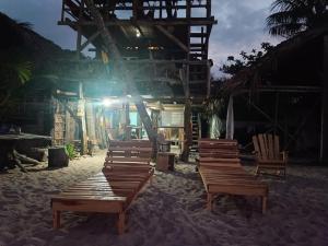 un grupo de sillas de madera sentadas en la arena frente a un edificio en Bob Marley Beach en Guachaca