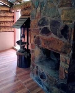 a stone fireplace in a room with a wooden floor at Hotel y Cabaña La Peña in Xilitla