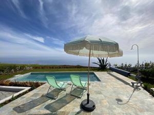 two chairs and an umbrella next to a swimming pool at The Hideaway Madeira in Prazeres