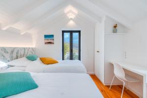 two beds in a white room with a window at The Hideaway Madeira in Prazeres