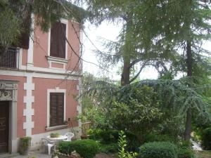 a pink and white building with a table and trees at Villa Genny in Candela