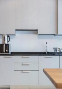 una cocina blanca con armarios blancos y fregadero en RivApartmentsDowntowN Urban en Riva del Garda