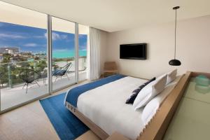 a bedroom with a large bed and a balcony at SLS Cancun in Cancún