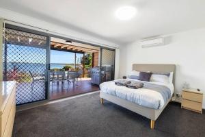 a bedroom with a bed and a balcony with a view at Almonta Apartments on the water front in Coffin Bay