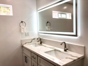 a bathroom with two sinks and a large mirror at Mākaha House in Waianae