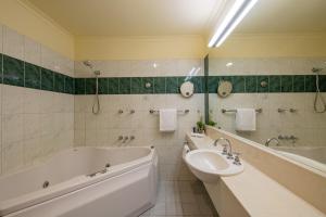 Baño blanco con bañera y lavamanos en Gateway on Monash en Clayton North