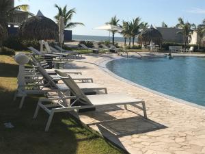 a row of lounge chairs next to a swimming pool at Playa Caracol Chame in Chame