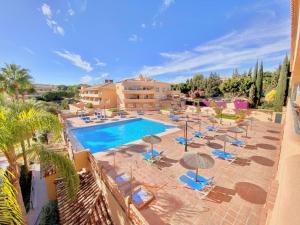 una piscina con sillas y sombrillas y un edificio en Apartamento en Los Patios de Santa Maria Golf, en Marbella