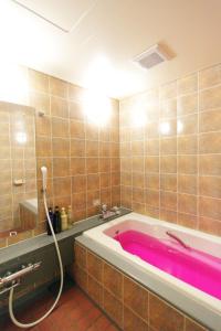 a bathroom with a pink bath tub in a room at 福井・鯖江のホテル｜ホテルモーメント in Sabae