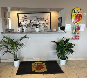 a restaurant with two potted plants and a counter at Super 8 by Wyndham Greeley in Greeley