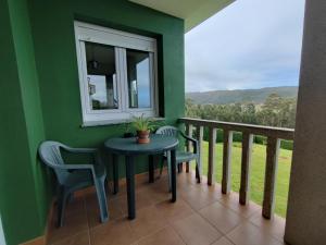 balcón con mesa, sillas y ventana en Casa as Milleiras - Serantes - Laxe, en Laxe