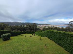 einen Garten mit Hecken und Blick auf das Wasser in der Unterkunft Casa as Milleiras - Serantes - Laxe in Laxe