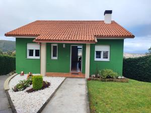 una casa verde con techo rojo en Casa as Milleiras - Serantes - Laxe, en Laxe