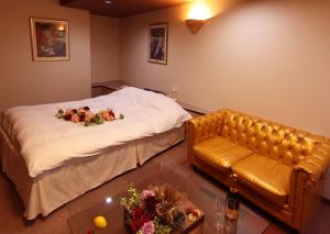 a bedroom with a couch and a bed with flowers on it at 福井・鯖江のホテル｜ホテルモーメント in Sabae
