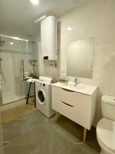 La salle de bains blanche est pourvue d'un lave-linge et d'un lavabo. dans l'établissement Apartamentos Toledo Casa de los Aljibes, à Tolède
