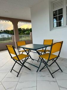 een glazen tafel en stoelen op een patio bij MAHOGANY in Le Vauclin