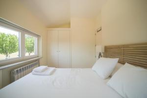 Un dormitorio con una gran cama blanca y una ventana en Vila Beiral, en Penafiel
