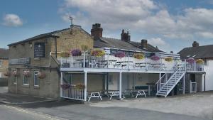 a building with a balcony with chairs and flowers at The Halfway House Inn in Leeds