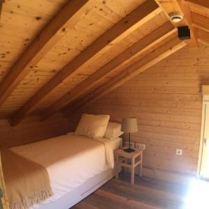 um quarto com uma cama num sótão de madeira em Vila Espigueiro I em Bustelo
