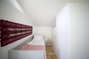 a small white room with a bed and a red blanket at Vila Fumeiro in Bustelo