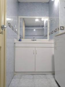 Baño blanco con lavabo y espejo en Acogedor Apartamento, en Quito