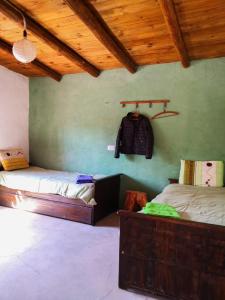 una habitación con 2 camas y una mochila en la pared en Cabaña Santa Rita - Tilcara en Tilcara