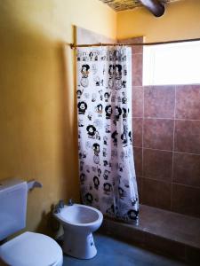 y baño con aseo y cortina de ducha. en Cabaña Santa Rita - Tilcara en Tilcara