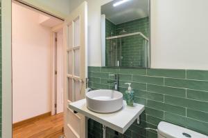 a bathroom with a sink and a green tiled wall at Piso céntrico San Simón in Santander