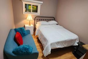 ein Schlafzimmer mit einem Bett und einem Sofa mit zwei Kissen in der Unterkunft Chesskings Guest House - Unit 2 in Winnipeg