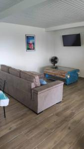 ein Wohnzimmer mit einem Sofa und einem Tisch in der Unterkunft Appartement neuf et tout confort sur la Trinité in La Trinité