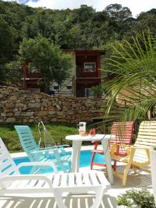 a patio with a table and chairs and a stone wall at Pousada Casa Donadello in Matilde
