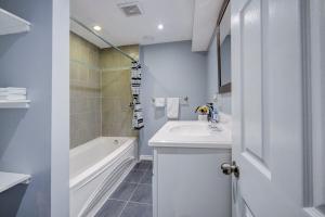 baño blanco con bañera, lavamanos y bañera tubermott en Paradise Waterfront Cottage (35 Min Drive From Toronto) en Georgina
