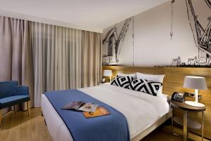 a bedroom with a large bed and a blue chair at Citadines Michel Hamburg in Hamburg +35 photos