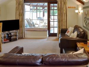 a living room with a leather couch and a television at Garden Cottage - Cp28 in Halwell