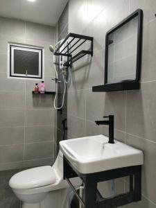La salle de bains est pourvue d'un lavabo, de toilettes et d'un miroir. dans l'établissement The Baiduri Courts, à Puchong