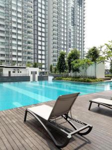 a lounge chair next to a swimming pool with tall buildings at QAISARA D'SAVANNA HOMESTAY@SOUTHVILLE CITY in Bangi