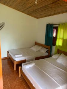 2 camas en una habitación con cortinas verdes en HOSTAL ESPERANZA en Palomino