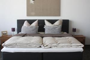 a large bed with white pillows on top of it at Silentio Apartments in Leipzig