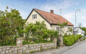 Biały dom z kamienną ścianą obok ulicy w obiekcie Stunning Home In Simrishamn With Wifi w mieście Simrishamn