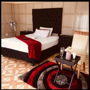 a bedroom with a bed with a red blanket and a table at Starpoint Guest house in Vereeniging