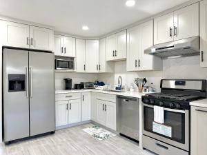una cocina con armarios blancos y electrodomésticos de acero inoxidable en 3 bedroom residential home in the lovely town near SFO San Francisco en Millbrae