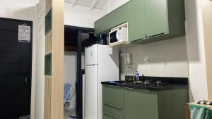 eine Küche mit grünen Schränken und einem weißen Kühlschrank in der Unterkunft Apartamento Praia do Forte in Mata de Sao Joao